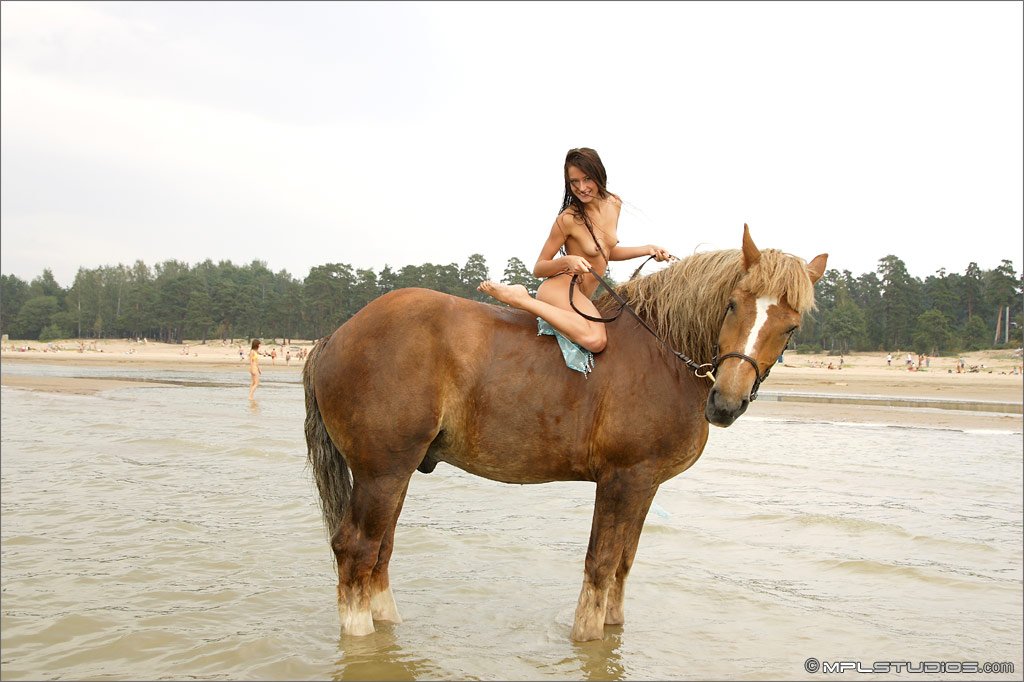 Нудистка с конем на берегу